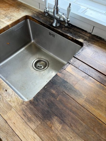 Damaged timber worktop and stained sink before replacement