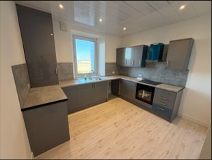 Completed dark grey L-shaped fitted kitchen
