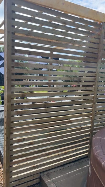 Horizontal timber slat privacy screening fixed to a garden decking and pergola frame