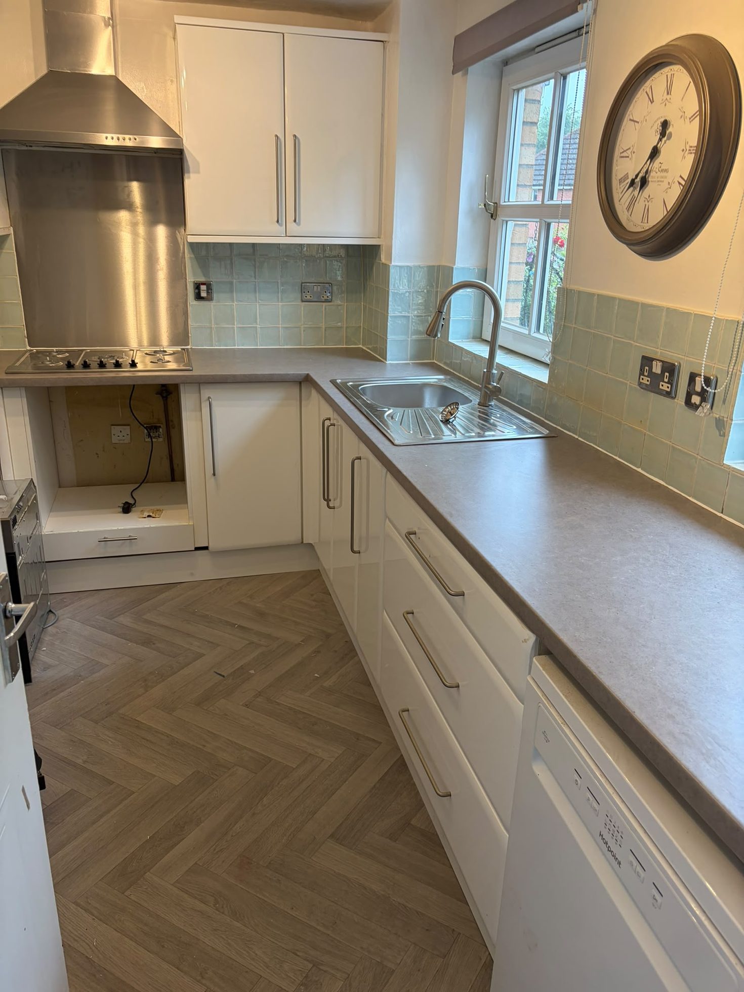 Fitted white kitchen with extractor, worktops, sink and herringbone flooring installed in Cumbernauld