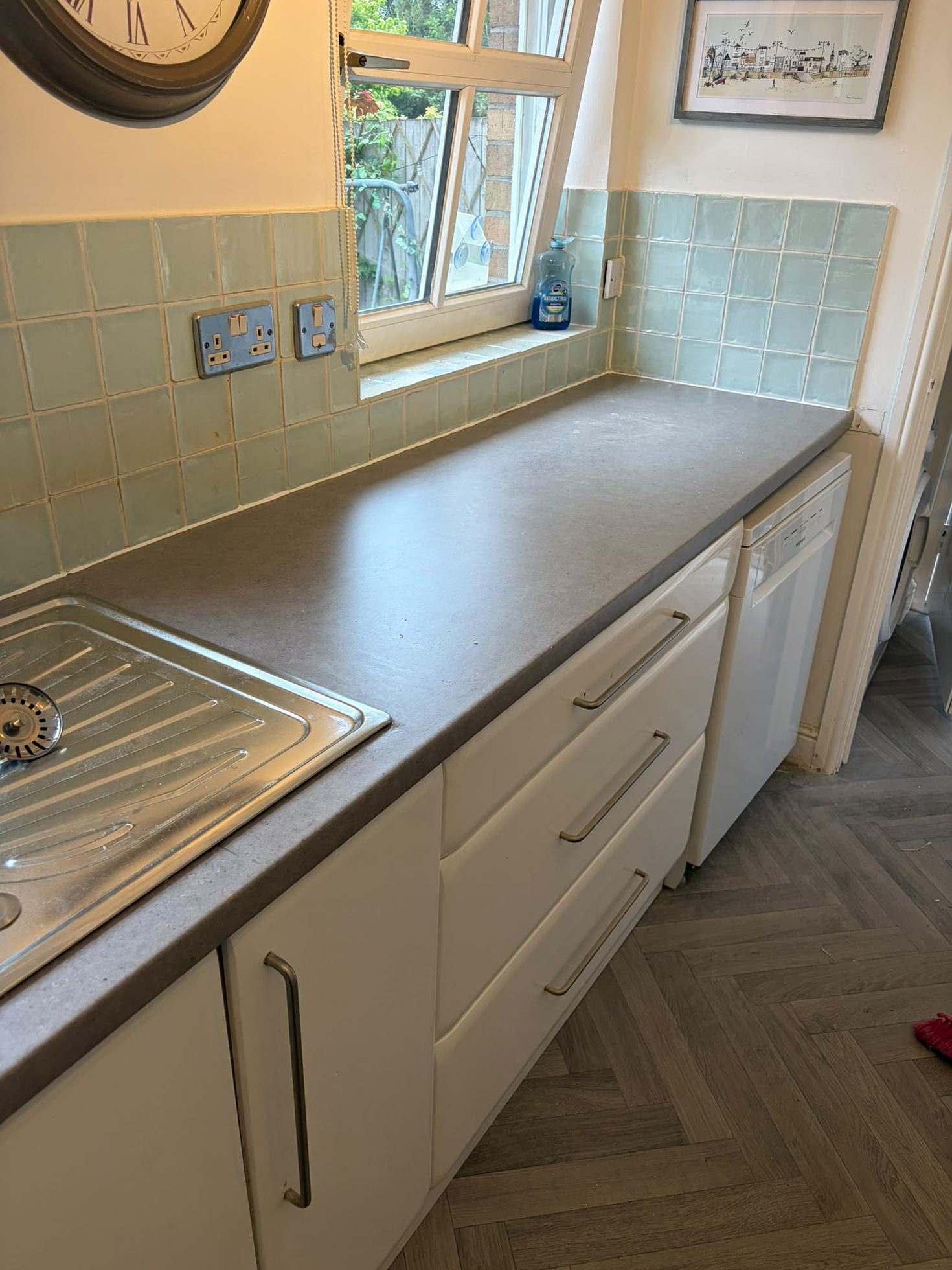 Fitted white cabinetry run with pale worktops, inset sink and tiled splashback by Impact Joinery