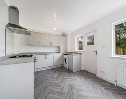 New white fitted kitchen with extractor and herringbone flooring after installation