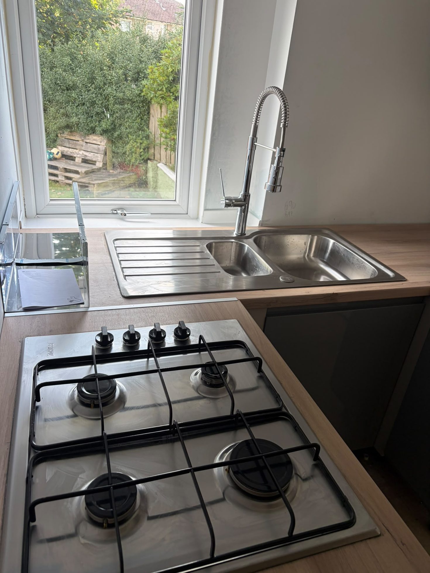 New gas hob and double stainless sink fitted into a wood-effect kitchen worktop